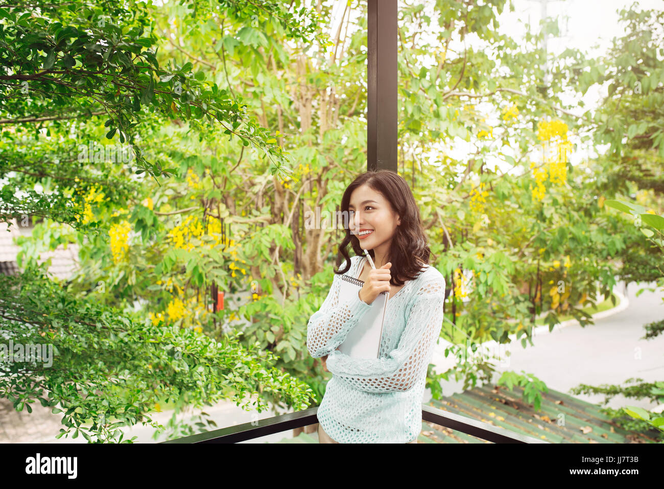 Junge attraktive süßes Mädchen mit Notepad auf einer Veranda. Frühling Stimmung. Stockfoto