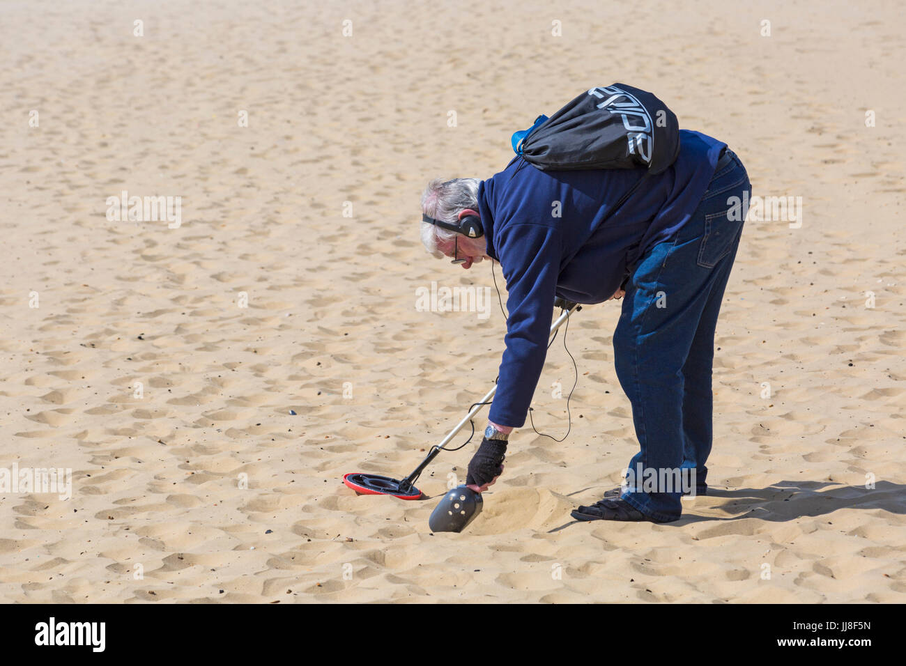 Treasure Hunter, Mann mit Metalldetektor auf der Suche nach einem Schatz am Strand von Bournemouth, Bournemouth, Dorset UK im Juli Stockfoto