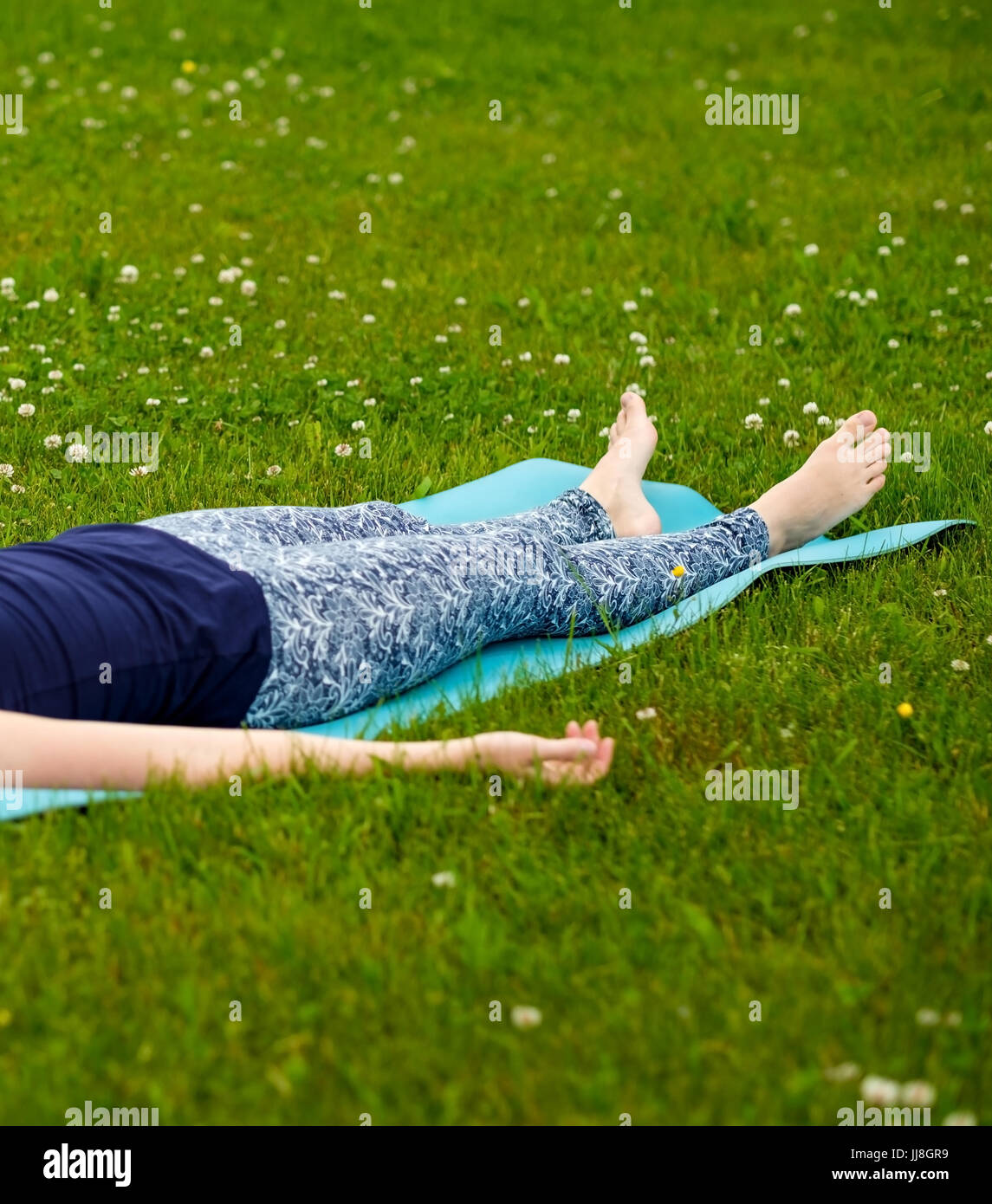 Kaukasische Frau tun, Yoga, Meditation, Shavasana oder Leiche Position im Park auf dem grünen Rasen Stockfoto