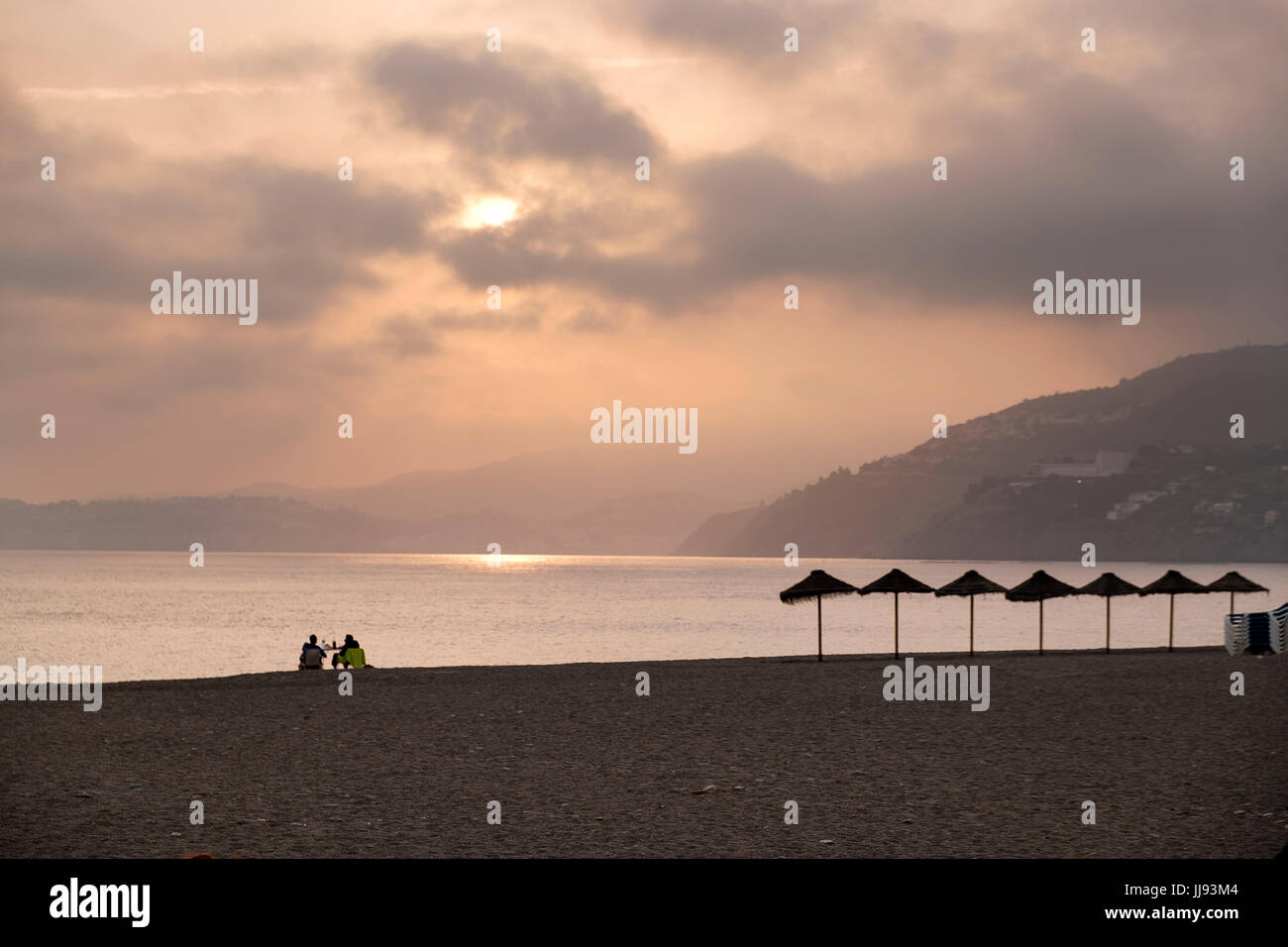 Zwei Personen an einem Tisch Getränken allein am Ostersonntag am langen Strand von Salobreña, Provinz Granada, Spanien Stockfoto