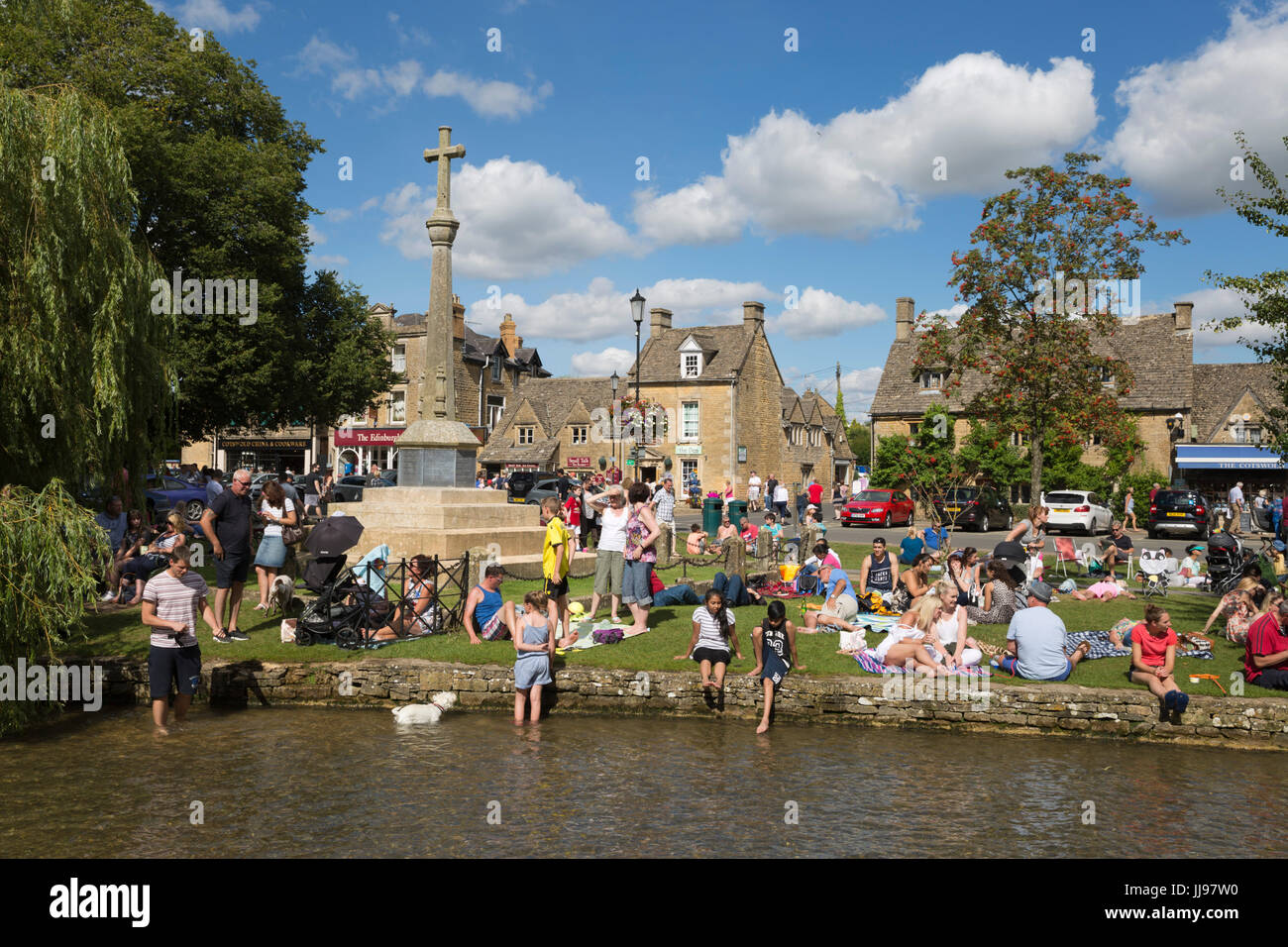 Masse der Leute neben River Windrush auf August Bank Holiday Wochenende, Bourton-on-the-Water, Cotswolds, Gloucestershire, England, Vereinigtes Königreich Stockfoto