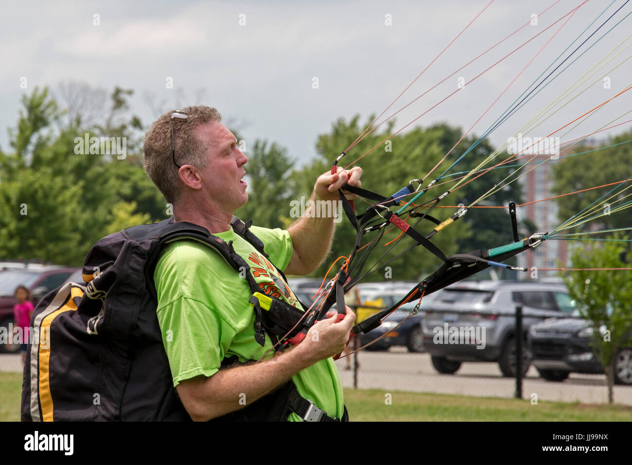 Detroit, Michigan - ein Gleitschirm-Pilot steuert sein Handwerk auf dem Boden an die Detroit Kite Festival, das auf Belle Isle. Über tausend Kinder eine Stockfoto
