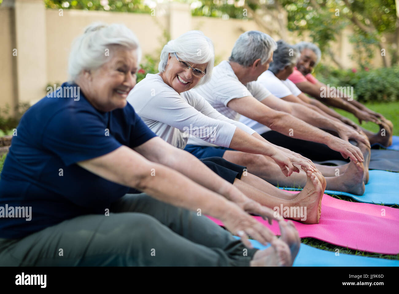 Fröhliche senior Frau mit Freunden tun stretching-Übung im park Stockfoto
