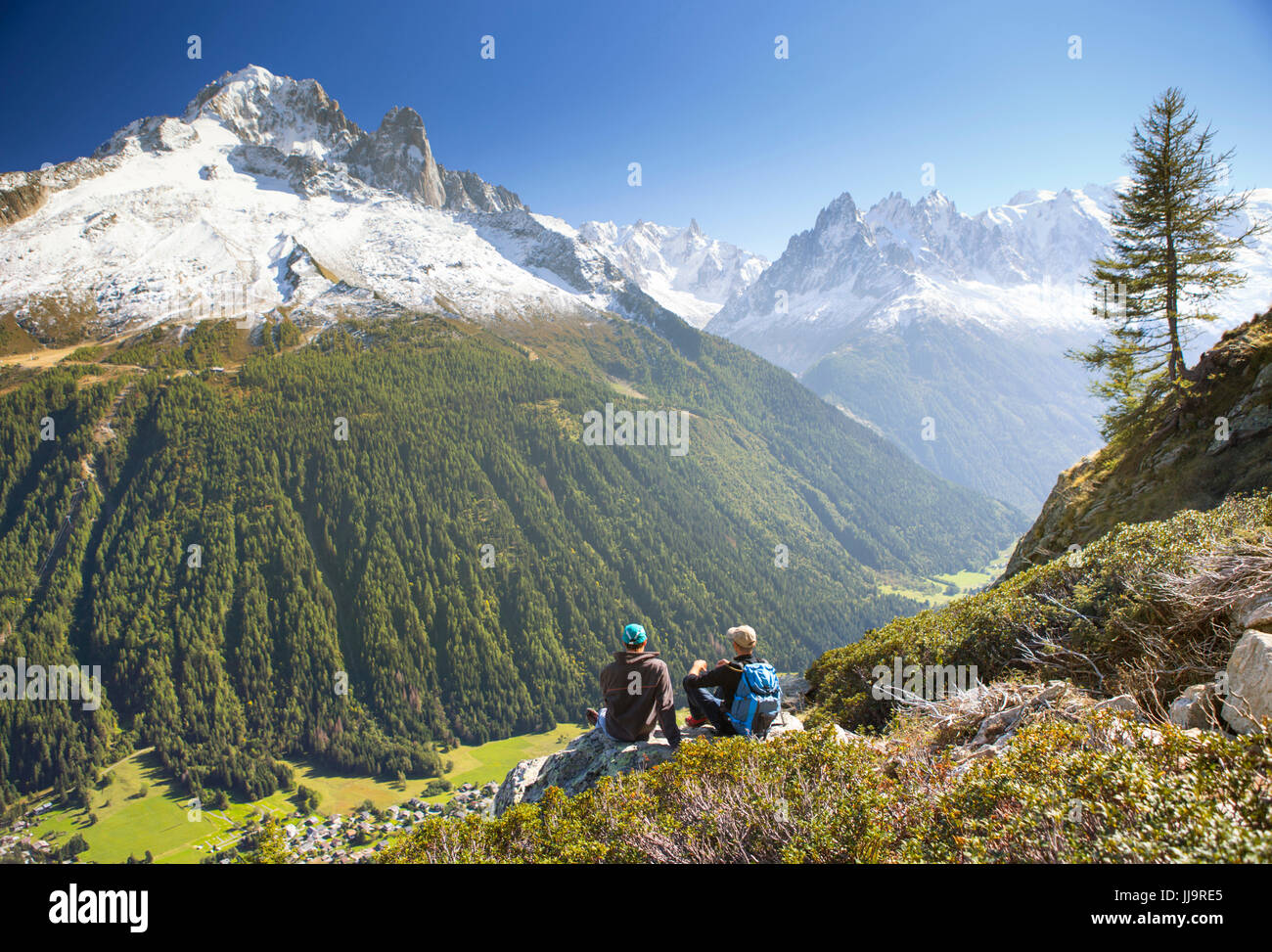 Zwei Wanderer erfreuen den Blick auf den Mont Blanc-Bergen, während der Einnahme einer Pause auf der Tour du Mont Blanc. Sie sind auf dem Weg zum Lac Blanc, über dem Tal von Chamonix. Stockfoto