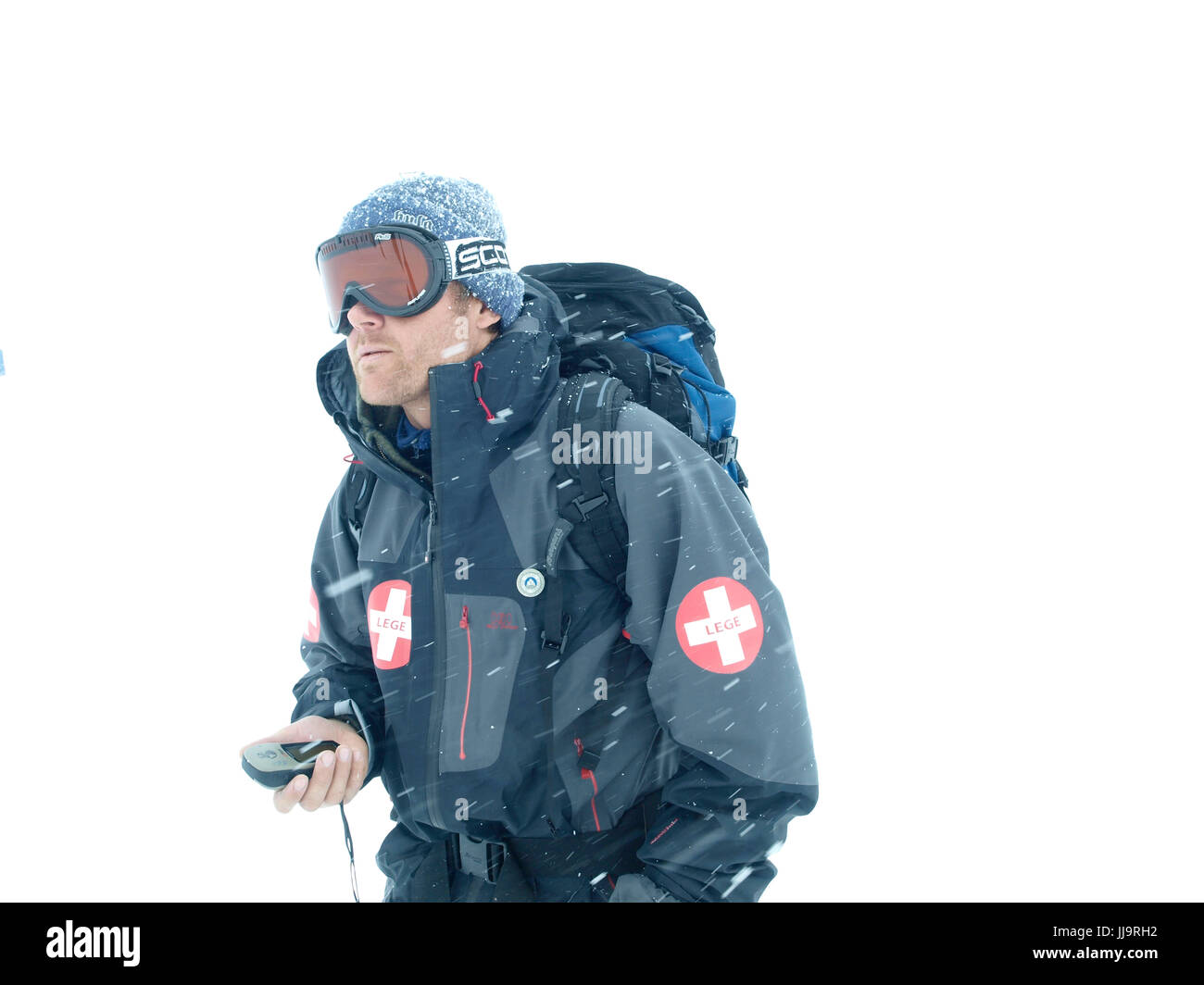 Ein norwegischen Bergführer ist in einem weißen Schnee Sturm mit einem Handheld-GPS-Gerät navigieren. Stockfoto