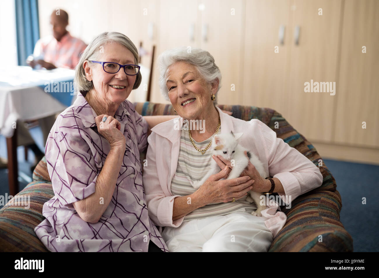 Porträt, Lächeln weiblichen Senioren mit Kätzchen sitzt auf Sessel im Altenheim Stockfoto