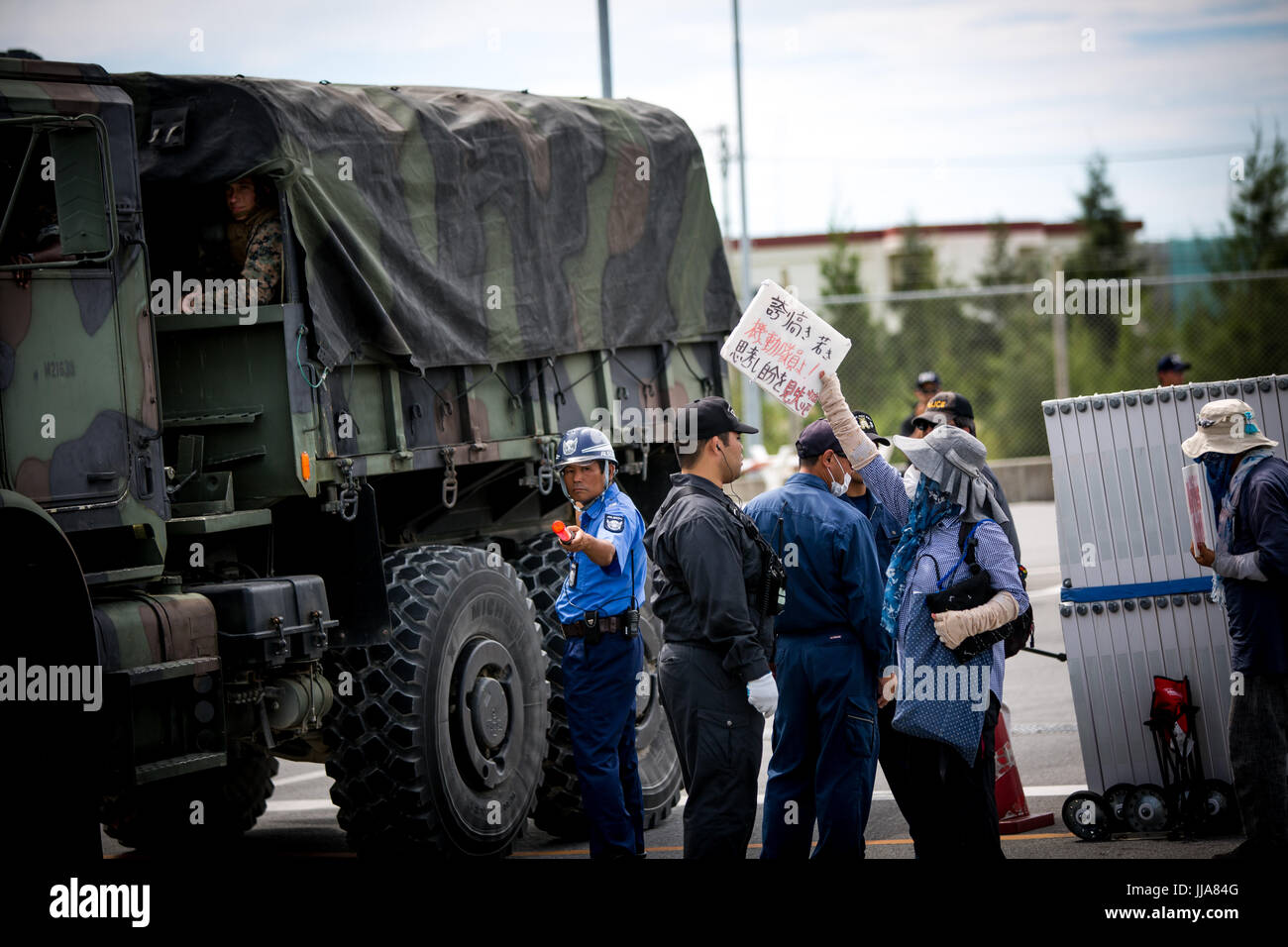 OKINAWA, JAPAN - 13 Juli: Anti-US-base Demonstranten mit Plakat versuchen, blockieren, US marine-Fahrzeug vor dem Camp Schwab-Tor zum protest gegen den Bau des neuen US-Marine base am 13. Juli 2017 in Henoko, Nago, Okinawa Präfektur, Japan. Demonstranten skandierten Parolen gegen die Pläne und Plakate prangerte die militärische Präsenz der USA, wie sie die Straße nach der Marine base in Henoko ausgekleidet statt. Bildnachweis: Richard Atrero de Guzman/AFLO/Alamy Live News Stockfoto