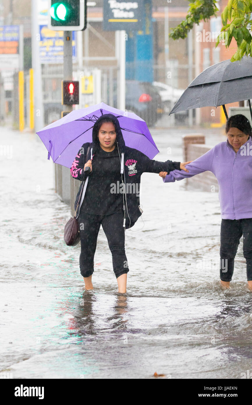 Zwei Frauen zu Fuß durch Flash-Überschwemmungen Wasser auf dem Heimweg nach Starkregen verursachte Sturzfluten, die A525 im Sommer während der Donner und Gewitter, die das Gebiet, Rhyl, North Wales, UK Stockfoto