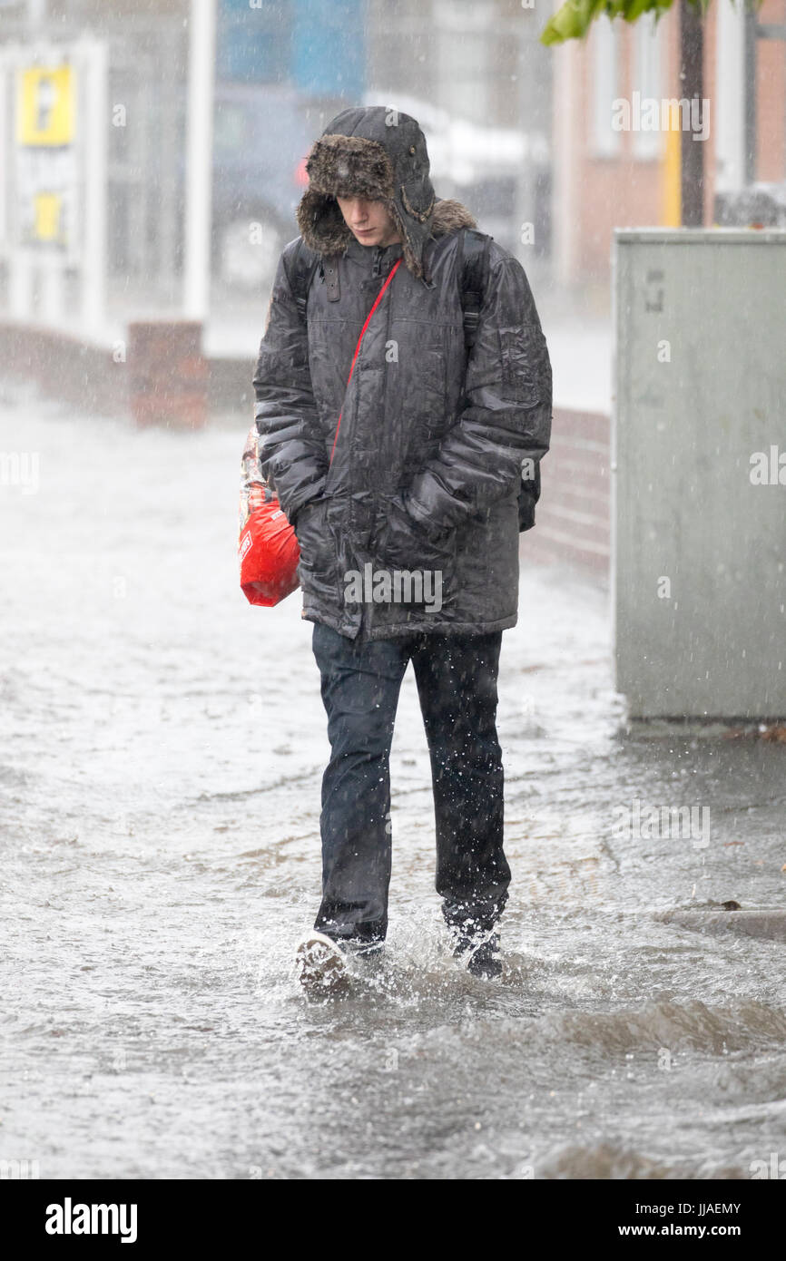 Ein Mann geht durch Flash-Überschwemmungen Wasser auf dem Heimweg nach Starkregen verursachte Sturzfluten, die A525 im Sommer während der Donner und Gewitter, die das Gebiet, Rhyl, North Wales, UK Stockfoto