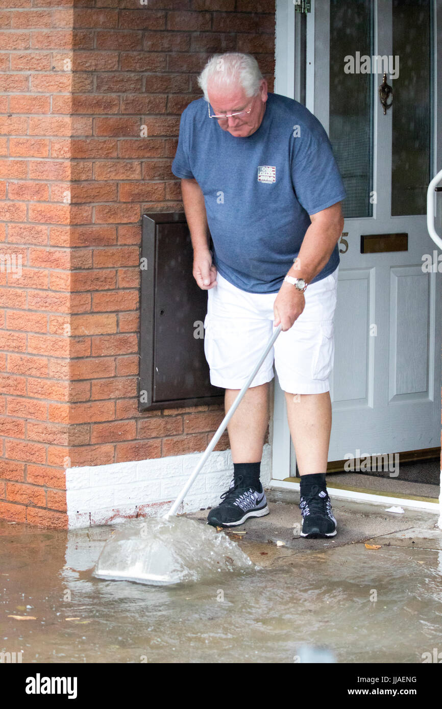 Älterer Mann versucht, sein Haus durch Bürsten sie von der Haustür entfernt, nach Starkregen Flash-Überschwemmungen in Teilen von Nord-Wales einschließlich Rhyl links Sturzflut Wasser fernzuhalten Stockfoto