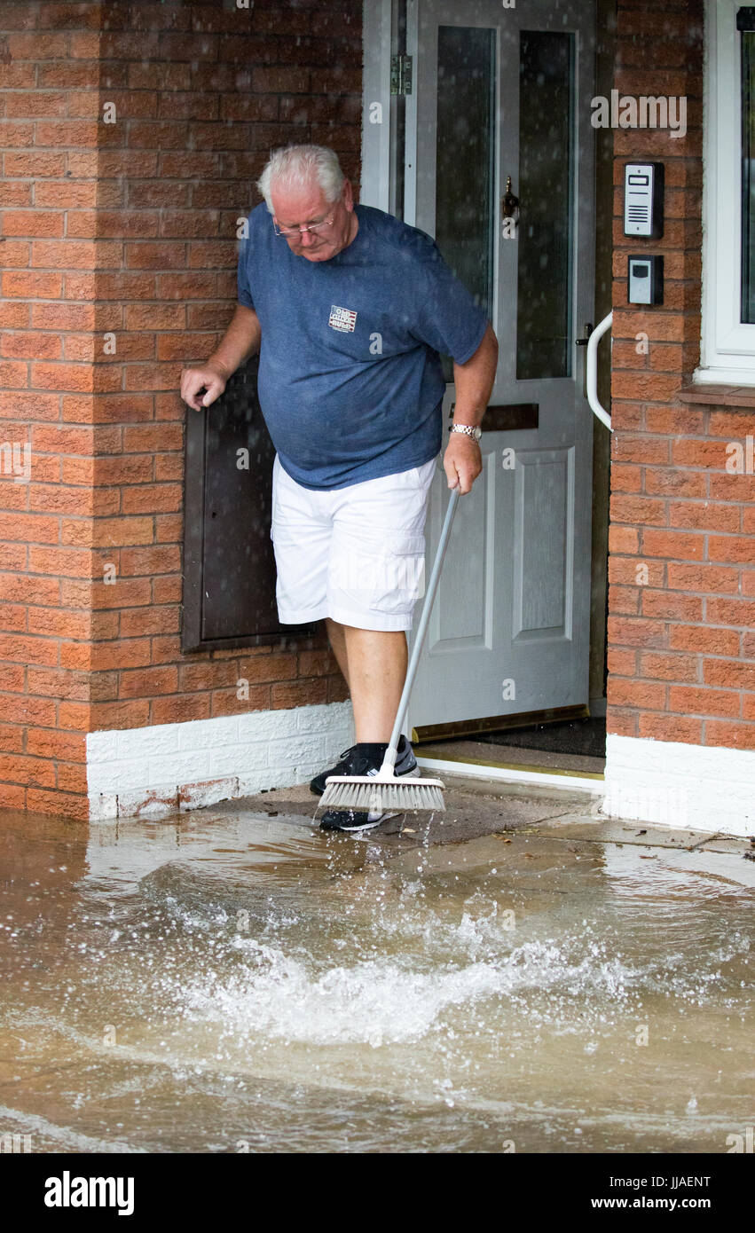 Älterer Mann versucht, sein Haus durch Bürsten sie von der Haustür entfernt, nach Starkregen Flash-Überschwemmungen in Teilen von Nord-Wales einschließlich Rhyl links Sturzflut Wasser fernzuhalten Stockfoto