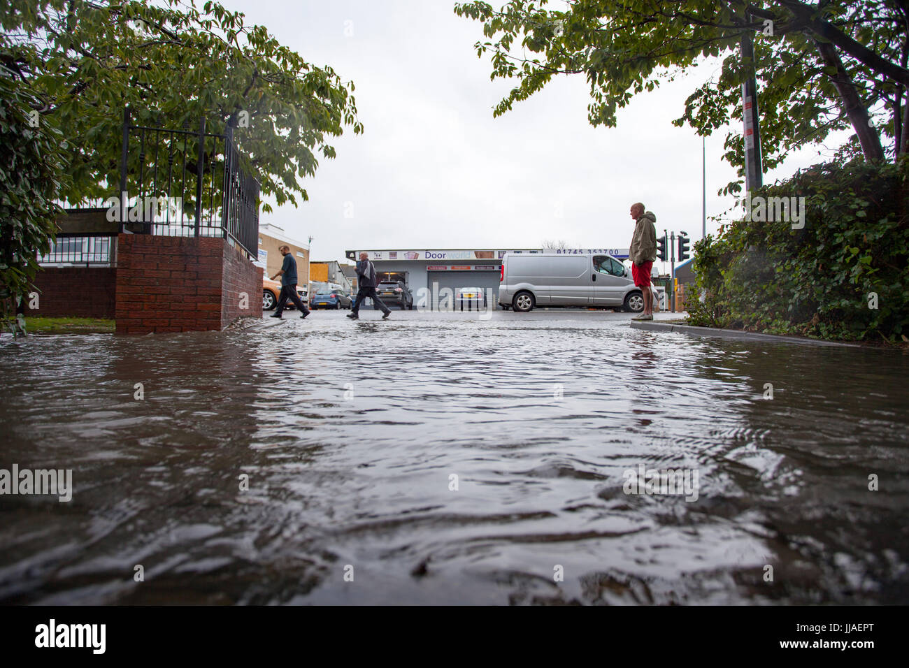 Menschen ertappt von sintflutartigen Regenfällen und Überschwemmungen während eines Sturms Sommer Spaziergang durch überflutete Straßen A525 unterwegs in den Küstenort Stadt Rhyl, Denbighshire, Wales, UK flash Stockfoto