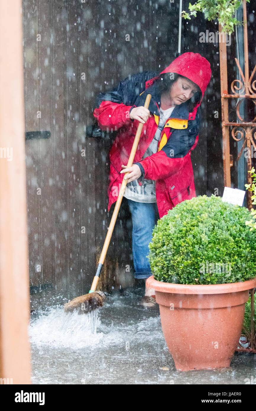 Ein Ladenbesitzer, die verzweifelt versuchen, grelle Flutwasser aus ihrem Geschäft zu halten durch Bürsten sie von der Haustür entfernt nach Starkregen linken Blitz Überschwemmungen in Teilen von Nord-Wales einschließlich Rhyl Stockfoto