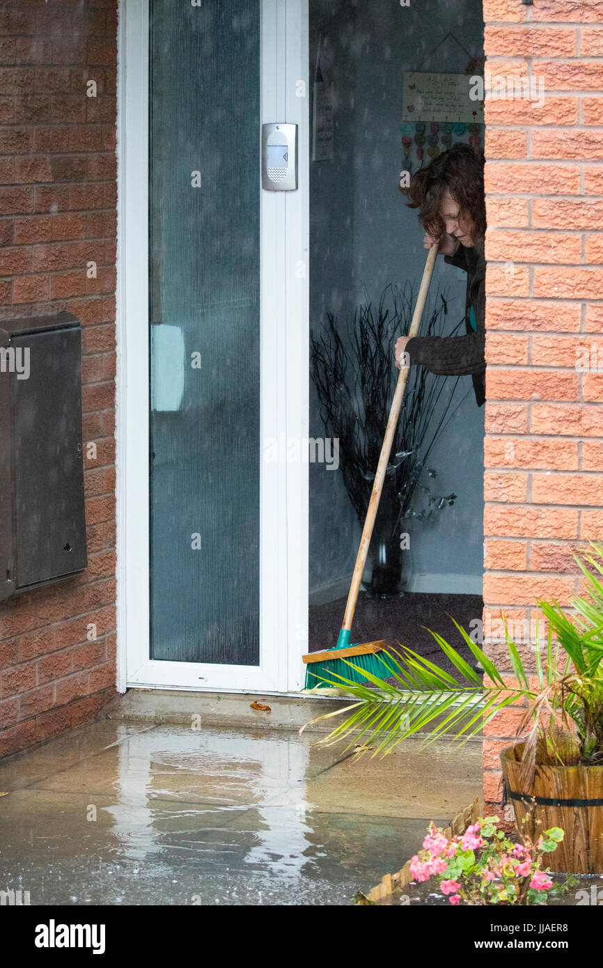 Ein Eigenheim besitzt, die verzweifelt versuchen, grelle Flutwasser aus ihrem Haus zu halten, durch Bürsten sie von der Haustür entfernt nach Starkregen linken Blitz Überschwemmungen in Teilen von Nord-Wales einschließlich Rhyl Stockfoto