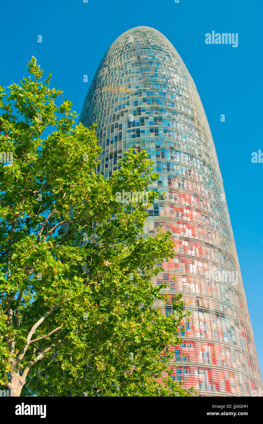 moderne Torre Agbar Wolkenkratzer in Poblenou Bezirk und grüner Baum gegen strahlend blauen Himmel, Barcelona, Katalonien, Spanien Stockfoto
