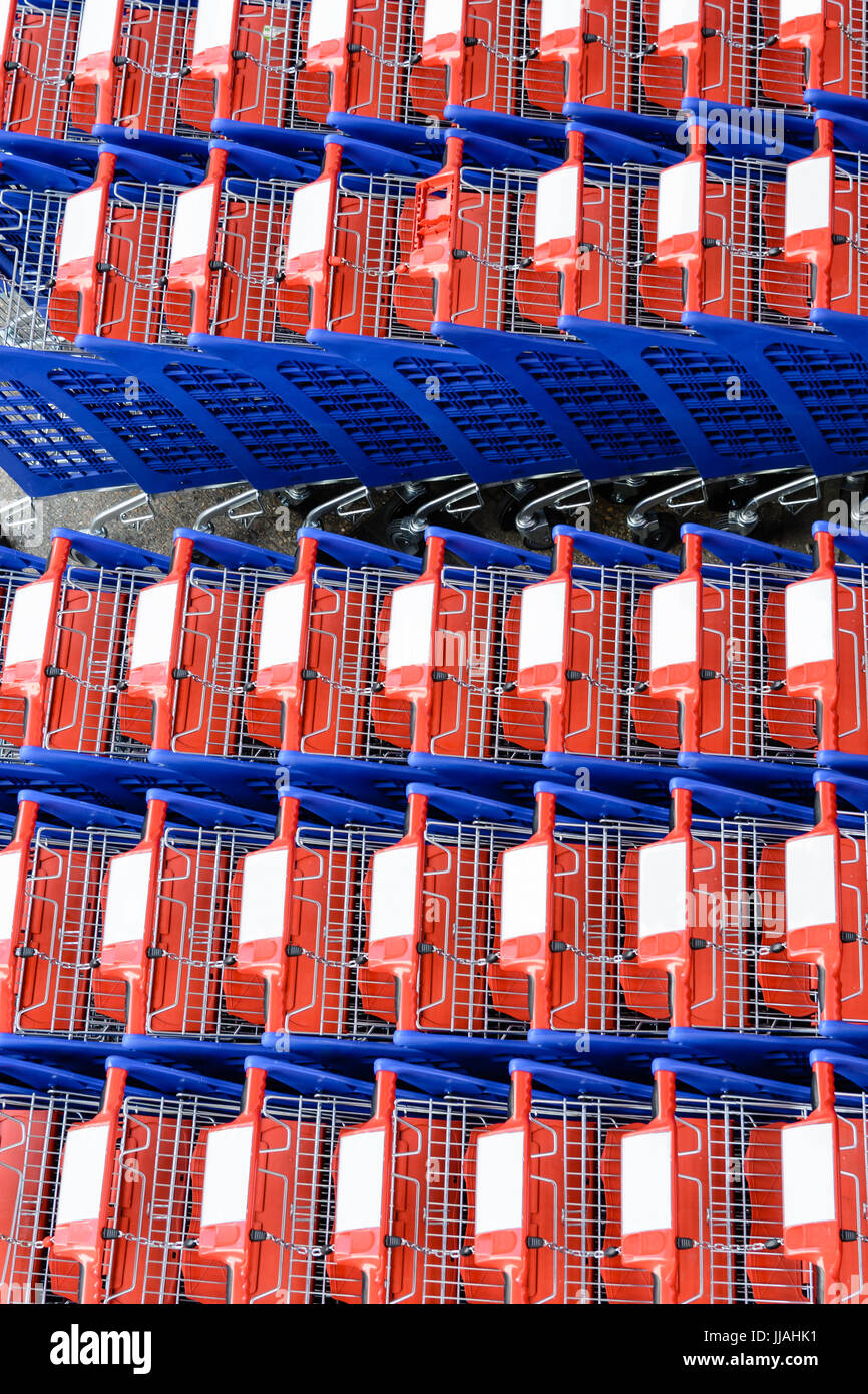 Blick von oben auf rote und blaue Einkaufswagen, die in mehreren Zeilen ineinander verschachtelt sind. Stockfoto
