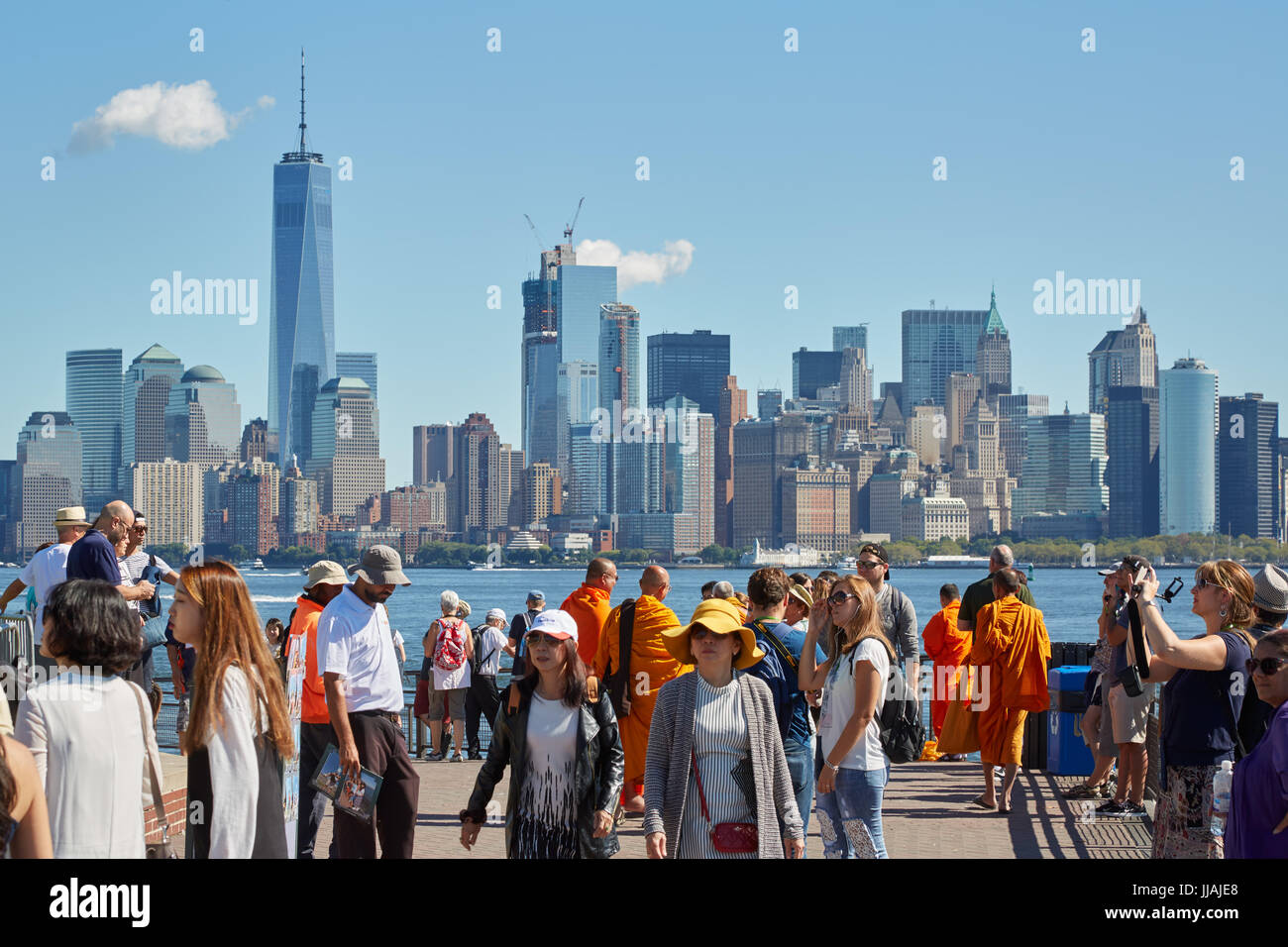 Menschen und Touristen fotografieren und mit Blick auf die Skyline von New York von Liberty Island an einem sonnigen Tag Stockfoto