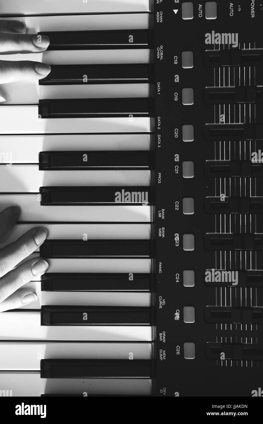 Weibliche Hände sind auf einem Synthesizer. Schwarz-weiß Foto. Blick von oben. Vertikale Foto Stockfoto
