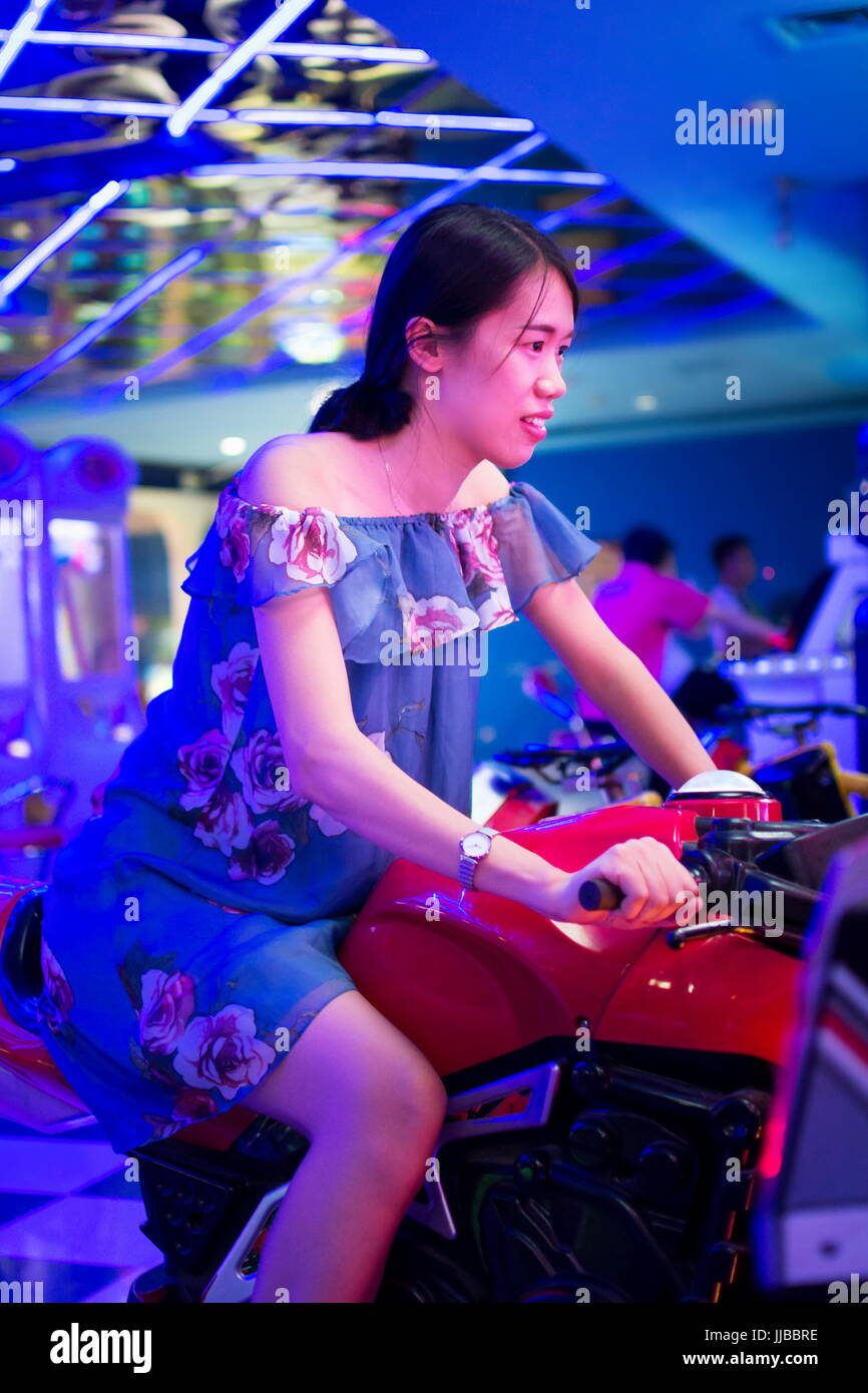Asiatin mit dem Spielzeug Motorrad in einem Arcade-Spielplatz Stockfoto