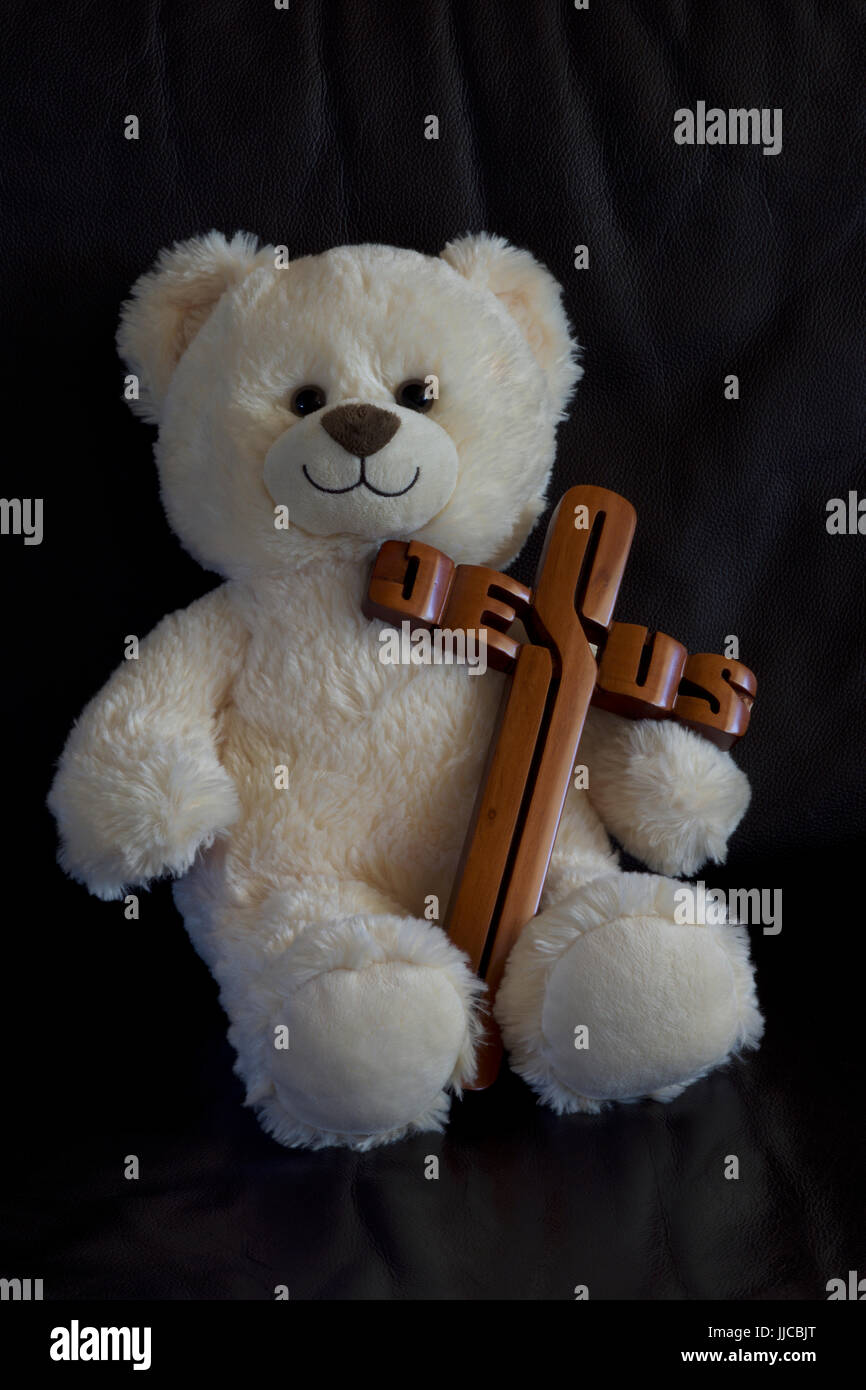 Weißer Teddybär trägt einen Jesus Kreuz Stockfoto