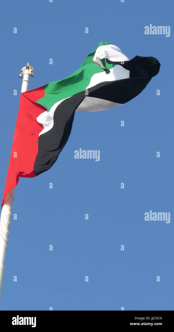 Eine riesige Flagge der Vereinigten Arabischen Emirate - VAE flattern im Wind, gegen klar blauer Himmel. Stockfoto
