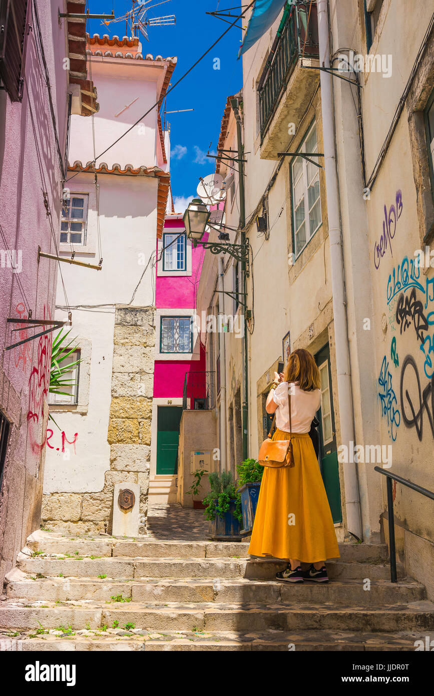 Frau touristische Stadt, Ansicht der Rückseite einer jungen Frau, die ein Foto einer Straße im bunten Stadtteil Alfama von Lissabon, Portugal. Stockfoto