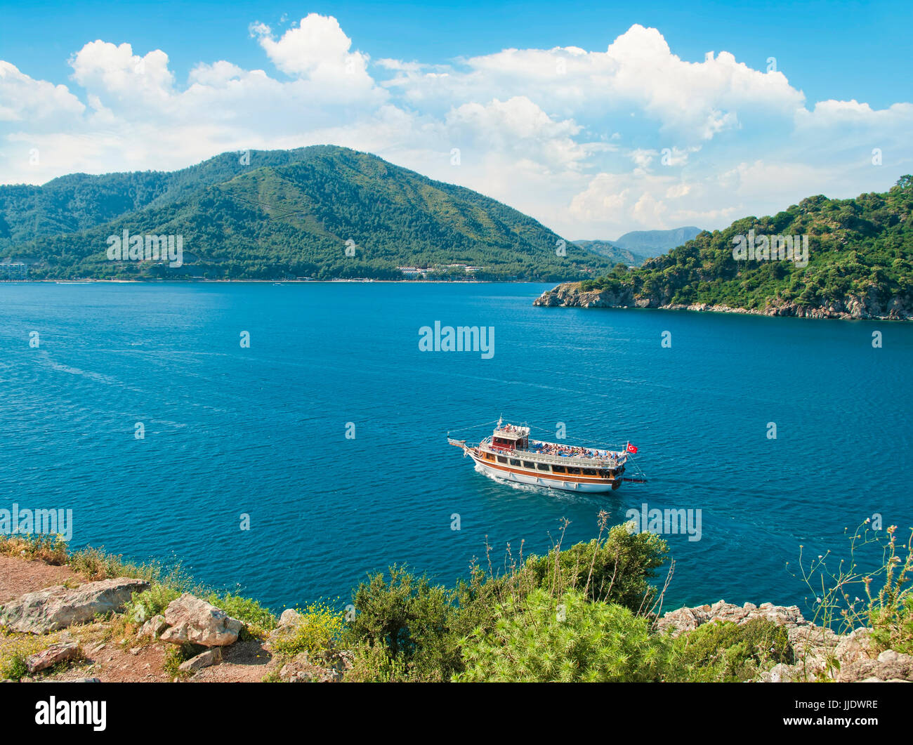 Blick auf touristischen Boot in der Bucht, umgeben von Bergen von einer felsigen Klippe an sonnigen Sommertag, Icmeler, Mugla, Türkei Stockfoto