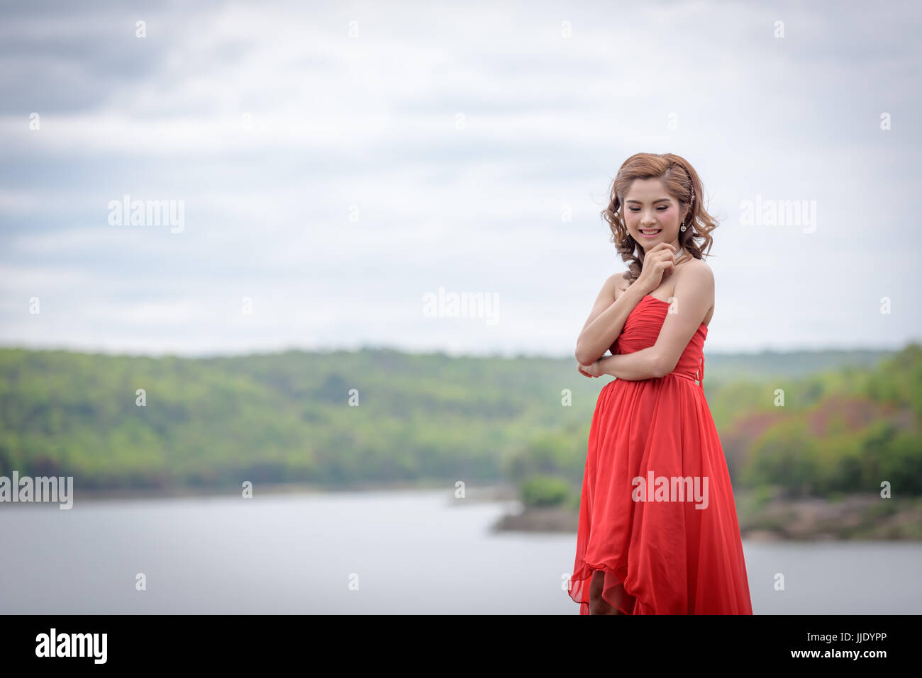 Schöne Frau tragen rote Abendkleid über Berge und Flüsse Hintergrund. Stockfoto