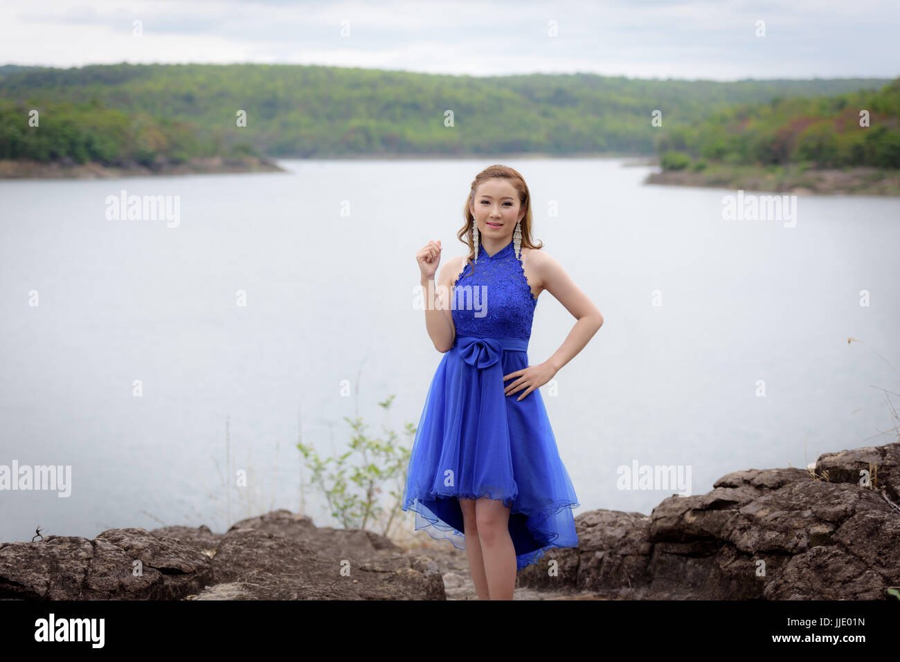 Schöne Frau tragen blaue Abendkleid über Berge und Flüsse Hintergrund. Stockfoto