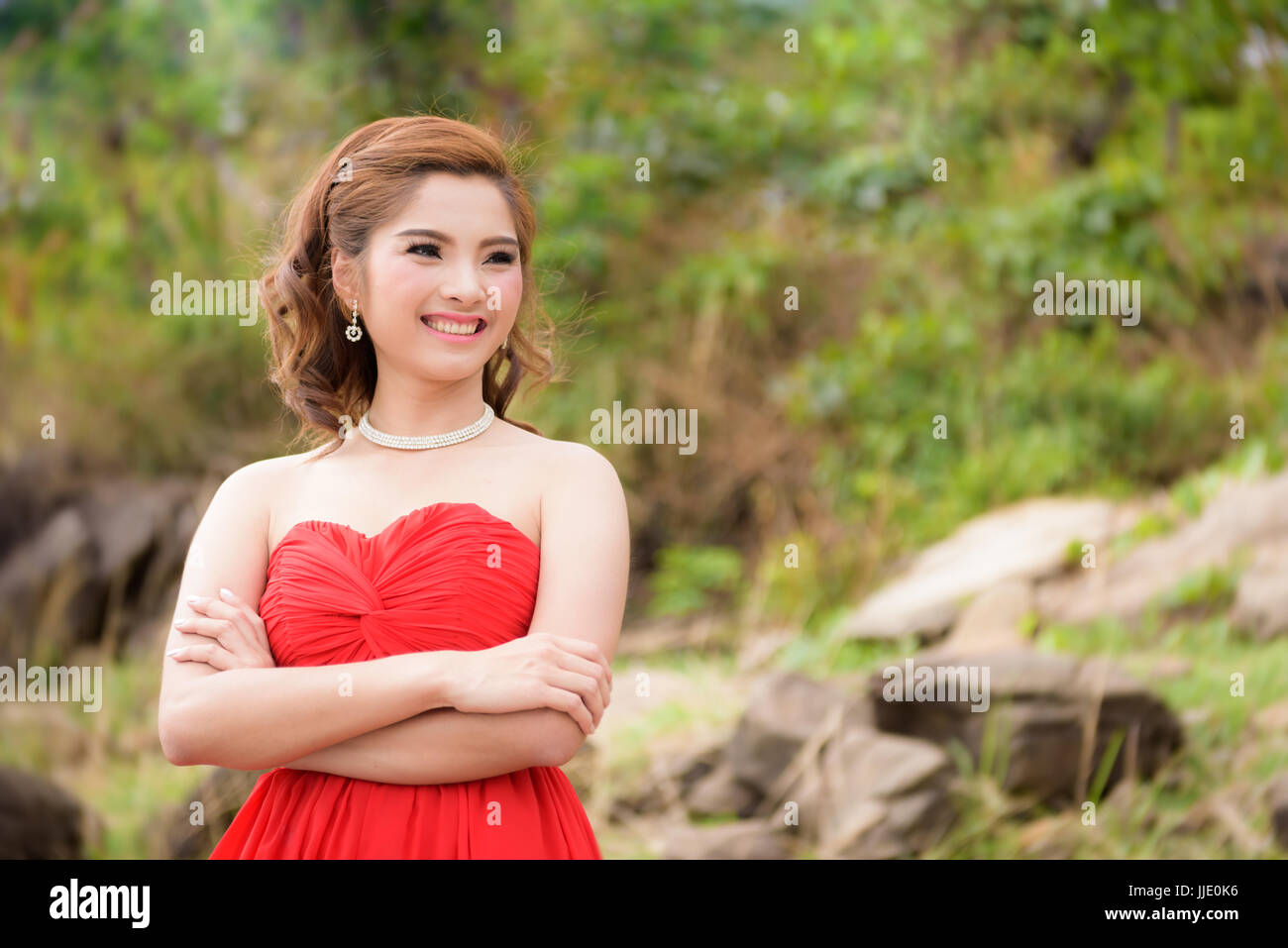 Schöne Frau tragen rote Abendkleid über Berge und Flüsse Hintergrund. Stockfoto