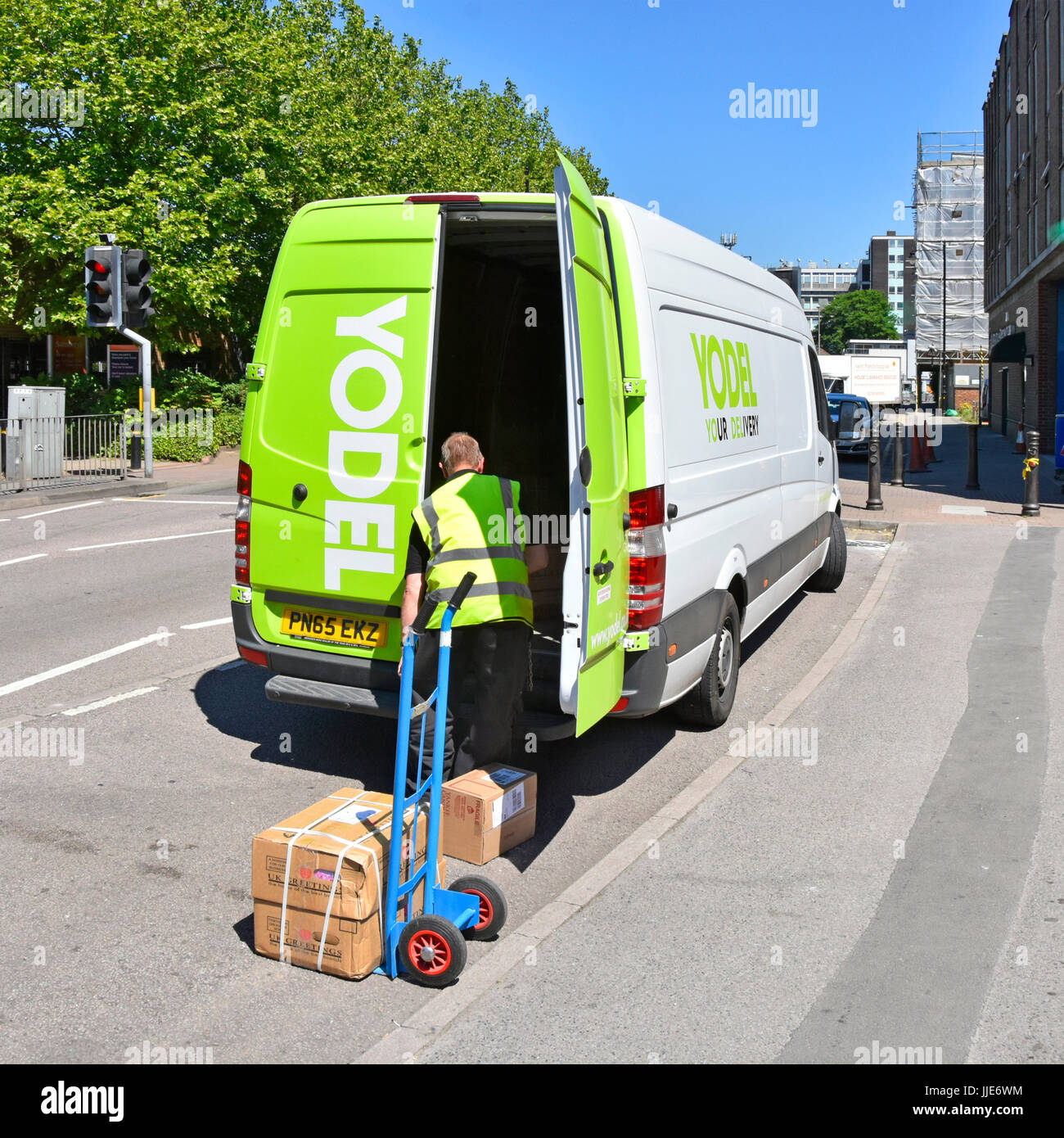 Jodel-Lieferwagen, der Pakete und Entladungen auf Rollkatzen transportiert, die Teil der nationalen britischen Lieferkette sind und Kisten zu nahegelegenen Straßengeschäften liefern Stockfoto