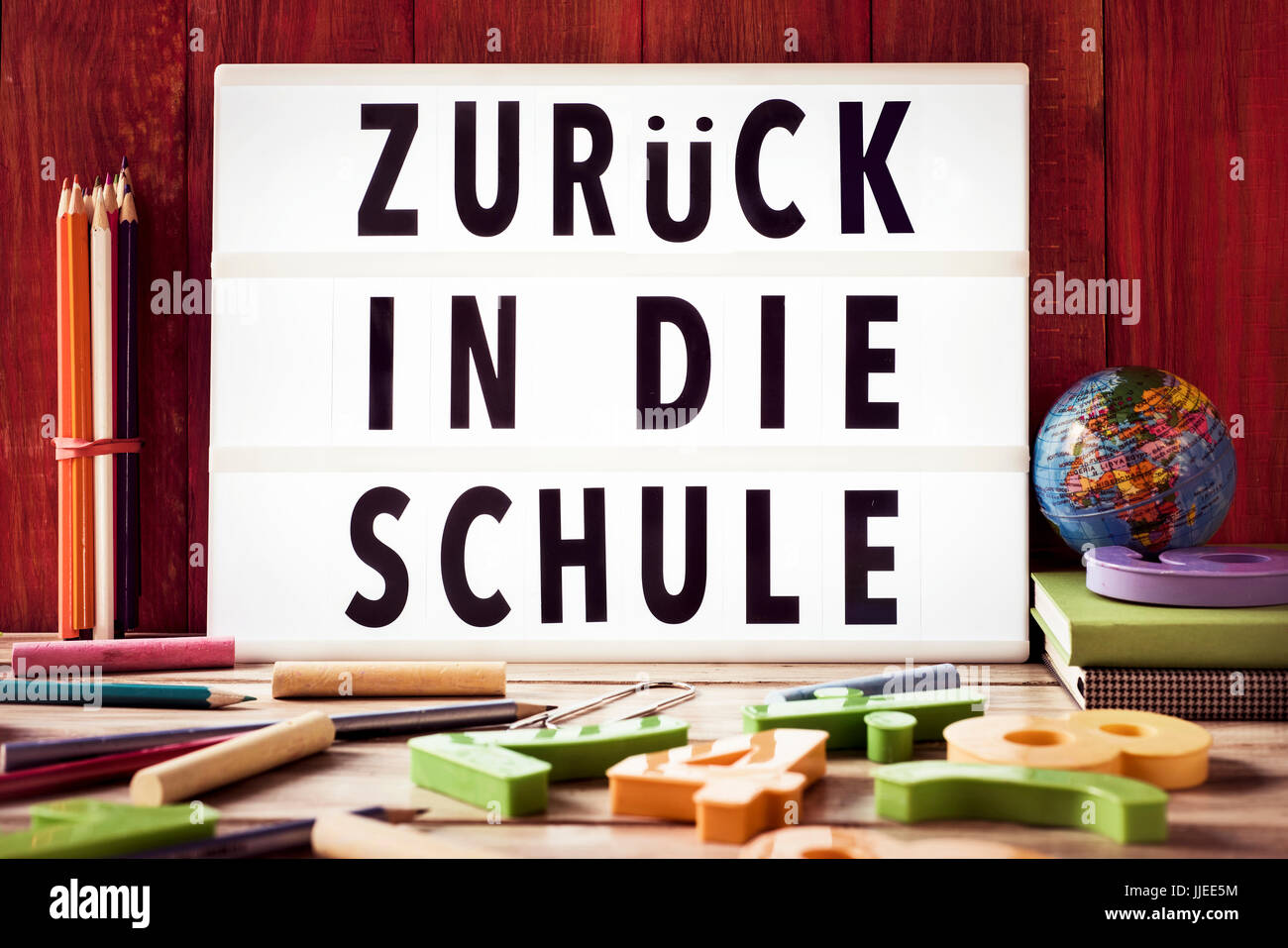 der Text zurück in Die Schule, zurück zur Schule in deutscher Sprache in einer Lightbox, einem rustikalen hölzernen Hintergrund platziert umgeben von dreidimensionalen taub Stockfoto