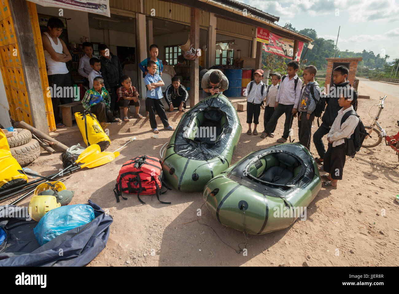 Robert Hahn bläst seine Packraft vor einem großen Publikum von Schuljungen in Ban Tang, Laos. Stockfoto