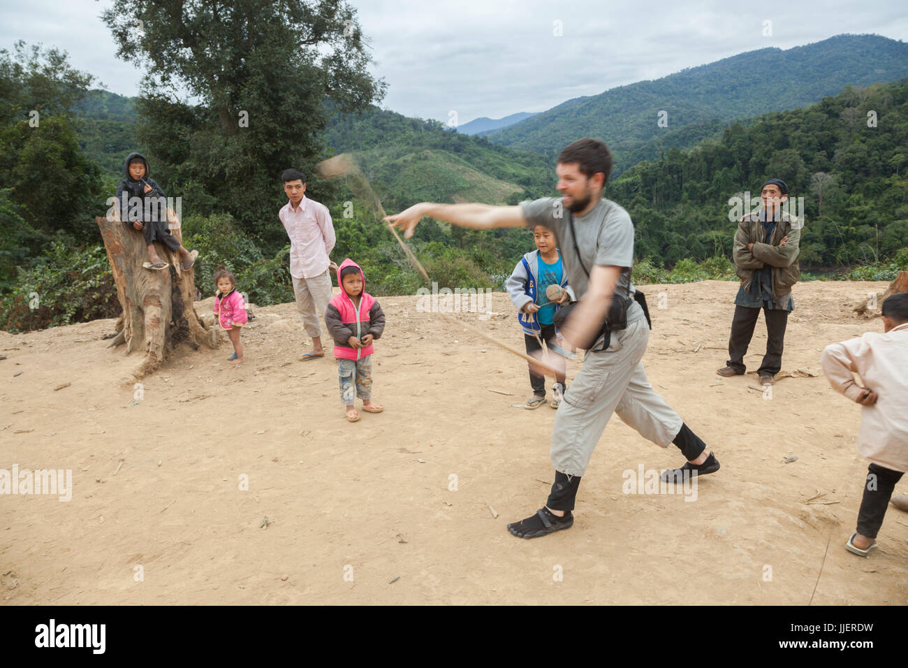 Robert Hahn versucht (erfolglos), einen Holz Kreisel mit Anweisungen von den Kindern am Ban Sop-Kha, Laos zu werfen. Stockfoto