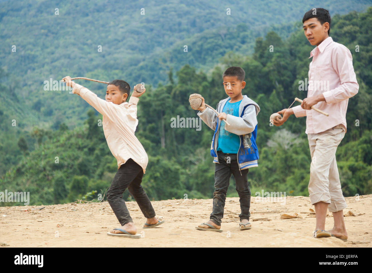 Ein Junge startet seine hölzernen Kreisel, wie andere ihre Gegenargumente in Ban Sop-Kha, Laos bereiten. Stockfoto