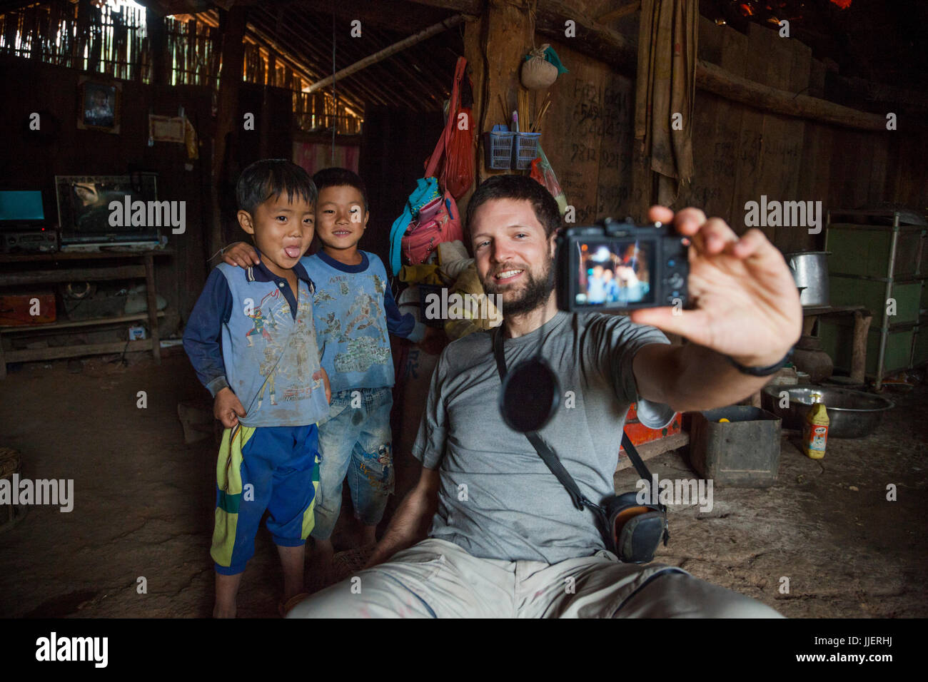 Robert Hahn nimmt ein Selbstporträt mit zwei jungen in ein Haus in Ban Sop-Kha, Laos. Stockfoto