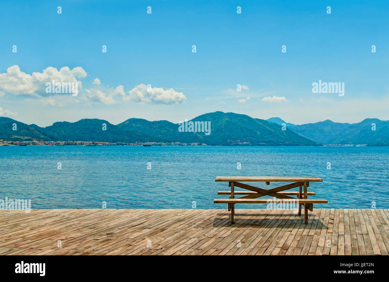 Holztisch mit zwei Bänken für Picknick stehen auf Holzböden auf dem Seeweg auf sonnigen Tag zugewandten grünen bergigen Inseln in der Nähe von Marmaris, Türkei Stockfoto