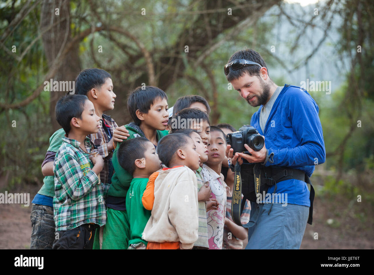 Robert Hahn zeigt Bilder von der Rückseite des seiner Digitalkamera zu einer Gruppe von neugierigen jungen versammelten sich am Strand in Muang Hut Hin, Laos. Stockfoto