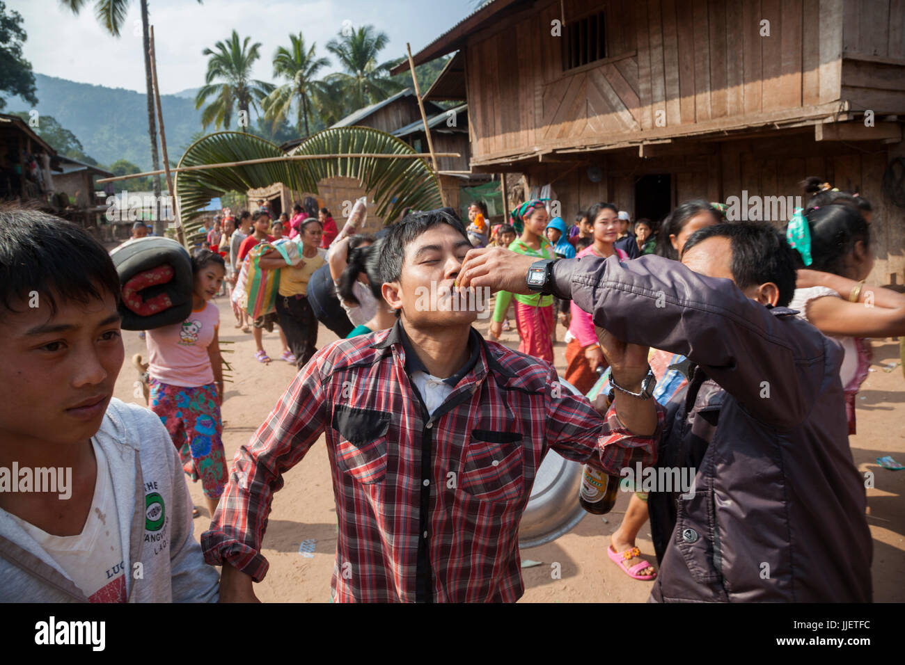 Ein Mann wird einen Schuss von Lao-Lao (Reis-Whisky) zu einer Hochzeit Prozession in Muang Hut Hin, Laos angeboten. Stockfoto