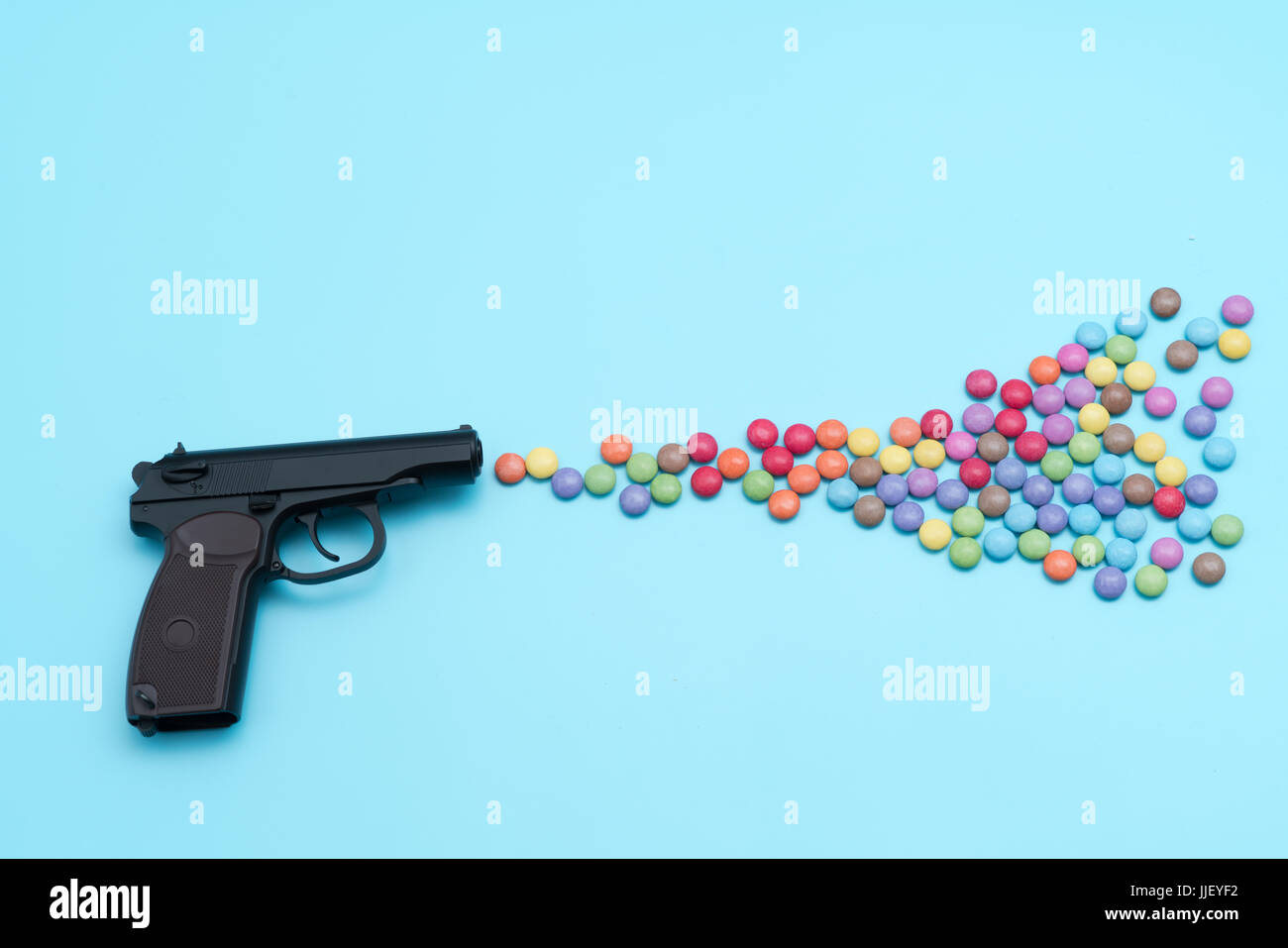 Pistole schießende Süßigkeiten, Applique Kunstwerk, Schuss aus einem Gewehr Aroma bunte Bonbons und Gummibärchen Stockfoto