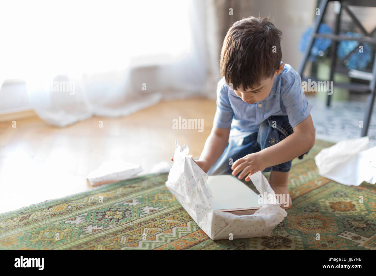 Junge sitzt auf Boden Auspacken eine Geburtstagsgeschenk Stockfoto