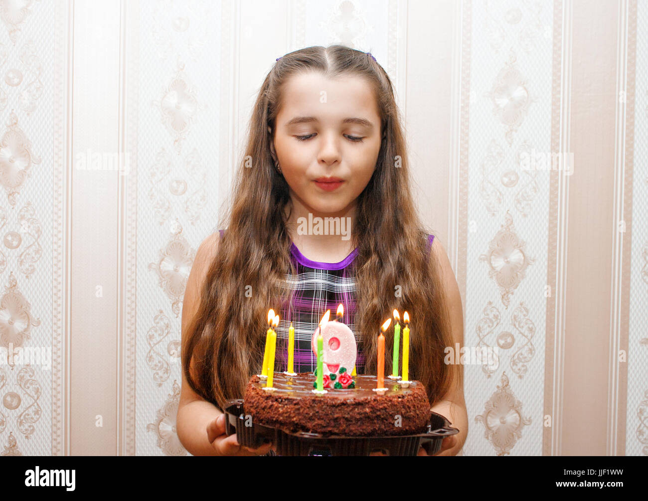 Mädchen bläst Kerzen auf ihrem Geburtstagskuchen Stockfoto