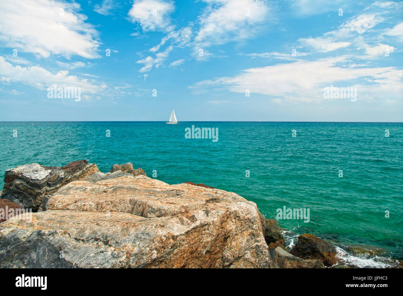 weißen Segelschiff am Horizont im Mittelmeer entnommen Felsenküste an sonnigen Sommertag in Santa Susanna, Katalonien, Spanien Stockfoto