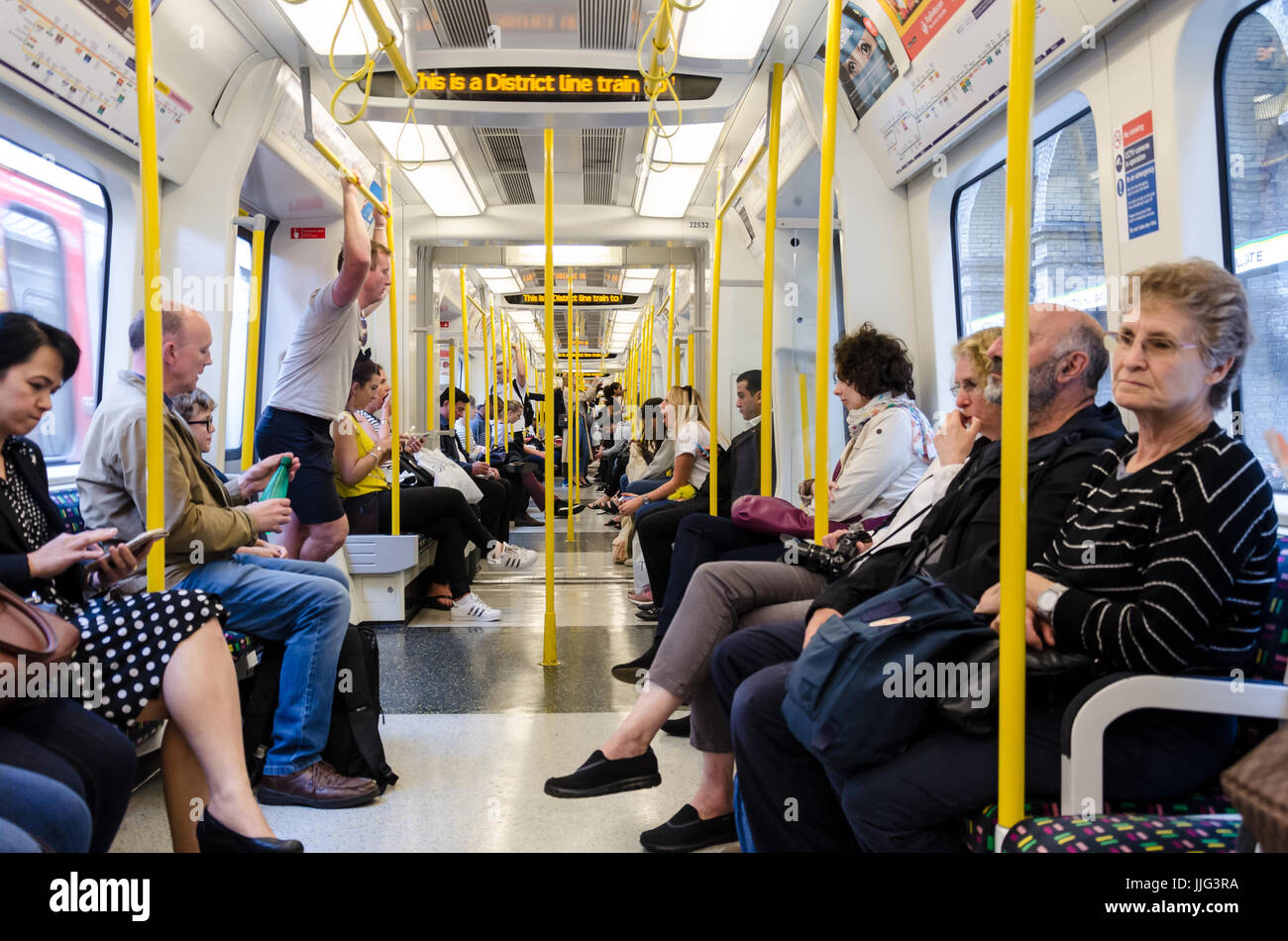 Menschen fahren einen District Line-Zug auf die Londoner U-Bahn. Stockfoto