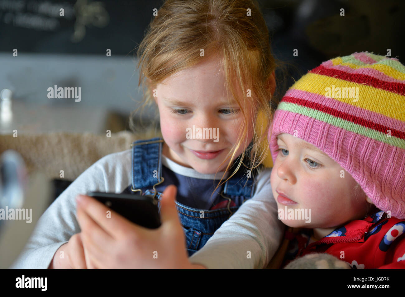 Zwei kleine Kinder schauen Sie sich ein Handy Stockfoto