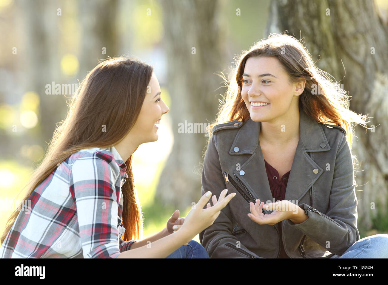 Zwei Freunde redeten und lachten, sitzen auf dem Rasen in einem park Stockfoto
