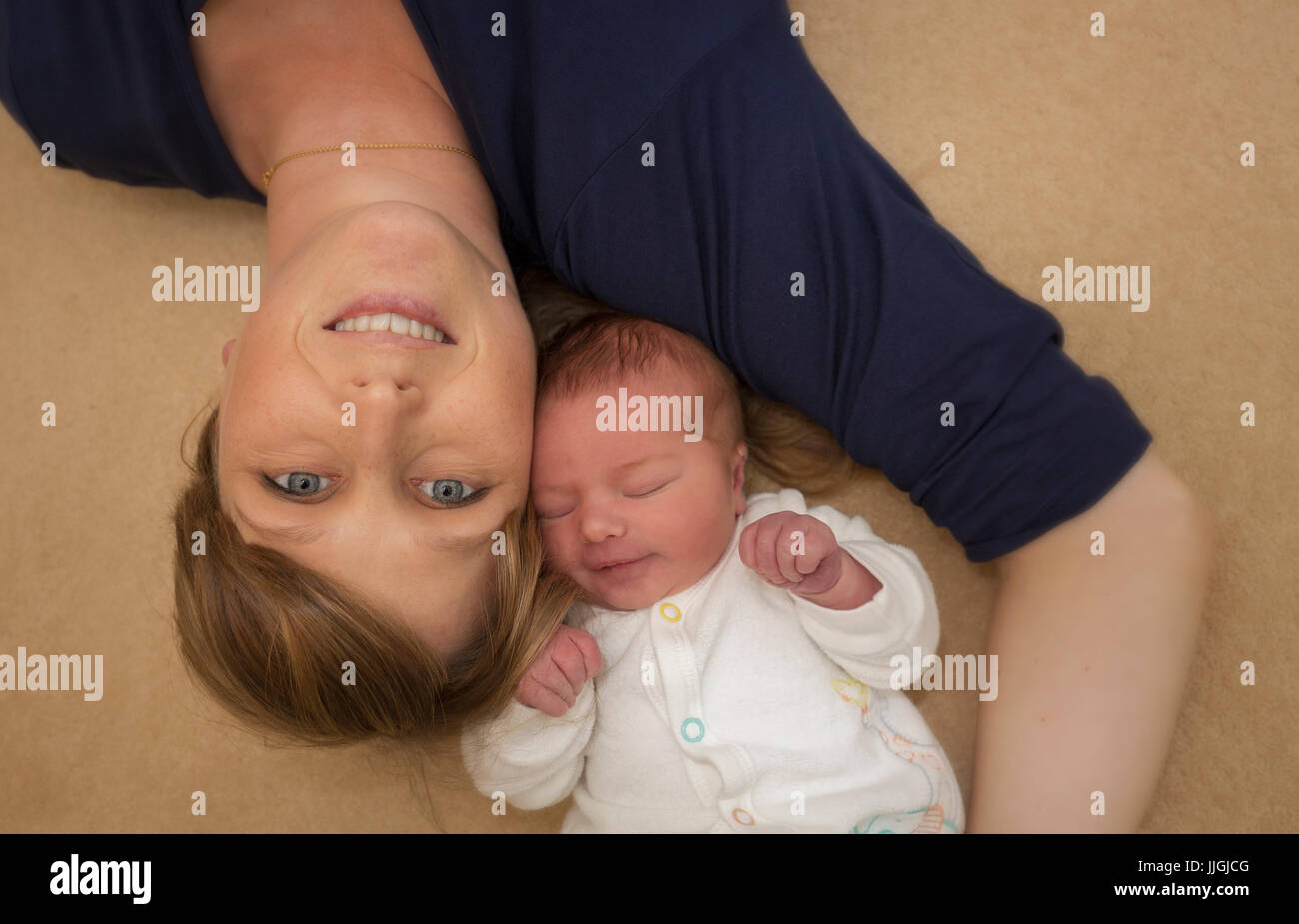 Neugeborenes Baby Boy mit seinem stolze Mutter auf dem Boden liegend Stockfoto
