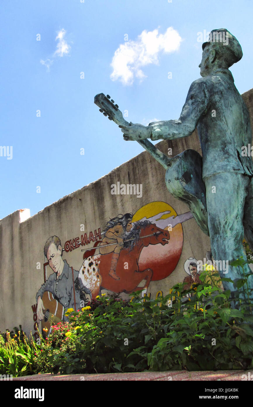 Ein Wandbild und Statue von Woody Guthrie mit seiner Gitarre steht in einem Park in seiner Heimatstadt Okemah, Oklahoma. Stockfoto