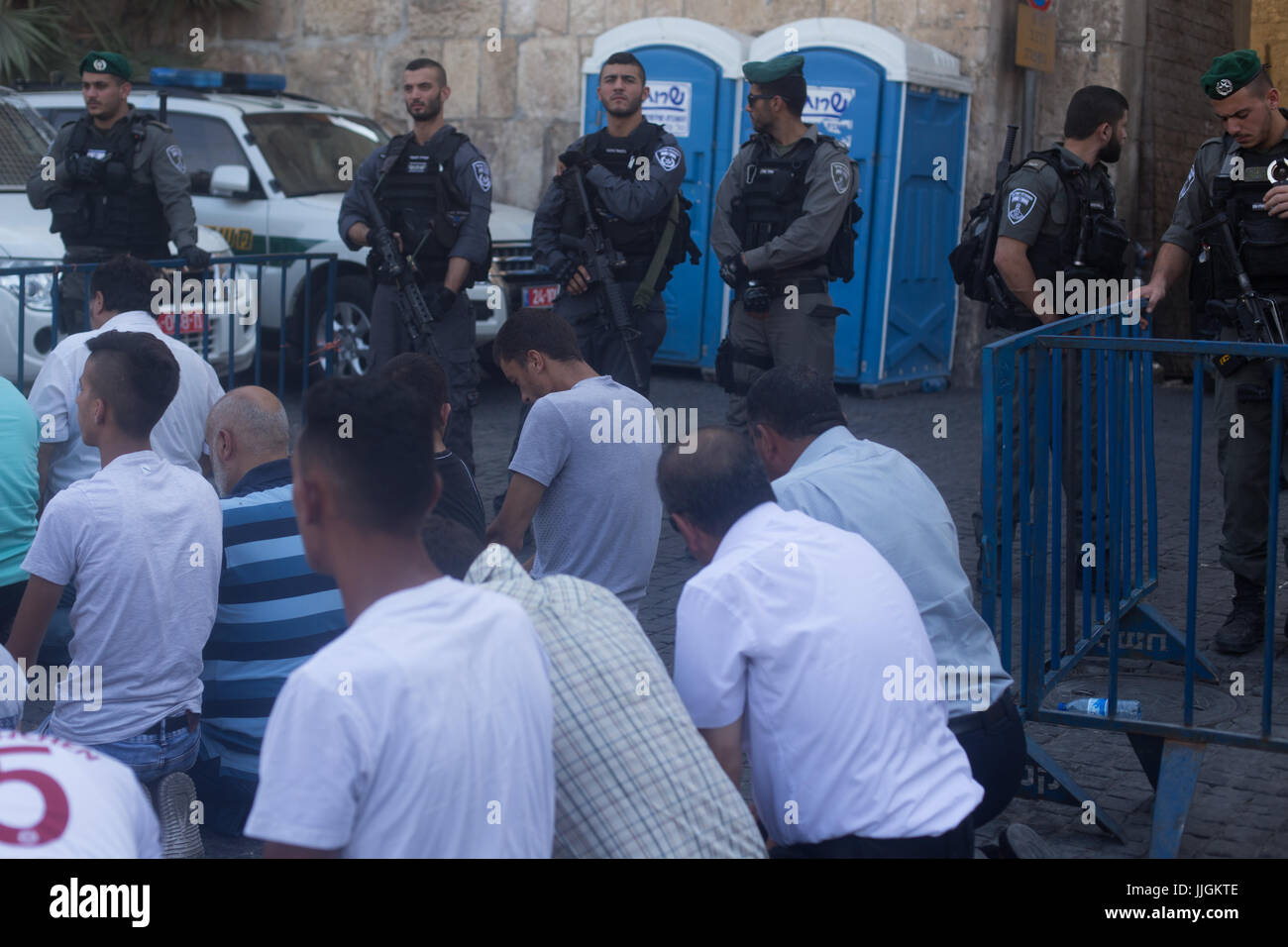 Jerusalem, Israel. 19. Juli 2017. Muslime halten Nachmittagsgebet außerhalb Löwentor, wie israelische Polizei aussehen auf. Auseinandersetzungen zwischen muslimischen Demonstranten und Polizei außerhalb Löwentor in die Altstadt von Jerusalem. Bildnachweis: Louise Wateridge/Pacific Press/Alamy Live-Nachrichten Stockfoto