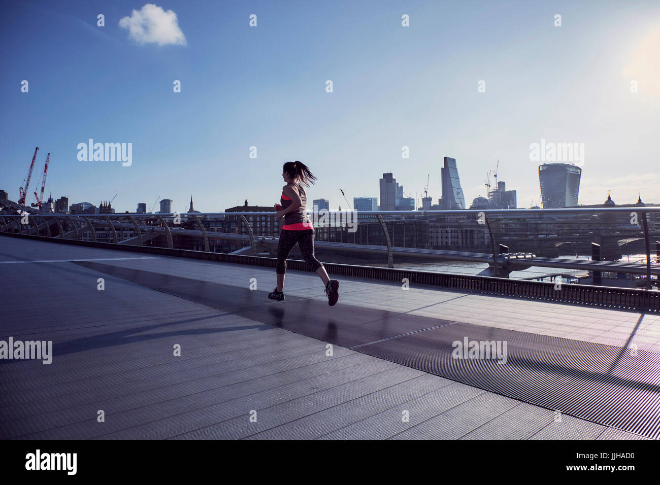 Eine Frau läuft über die Millennium Bridge in London. Stockfoto